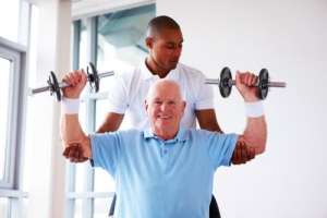 elderly man doing physical therapy assisted by a caregiver